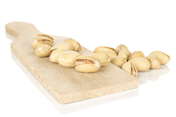 Lot of whole salted pistachio on wooden cutting board isolated on white background