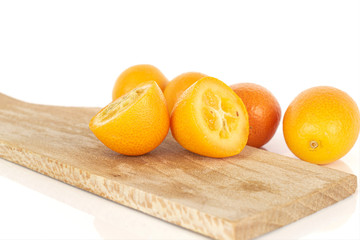 Group of four whole two halves of tasty orange kumquat on wooden cutting board isolated on white background