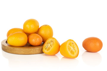 Group of lot of whole two halves of tasty orange kumquat on round bamboo coaster isolated on white background