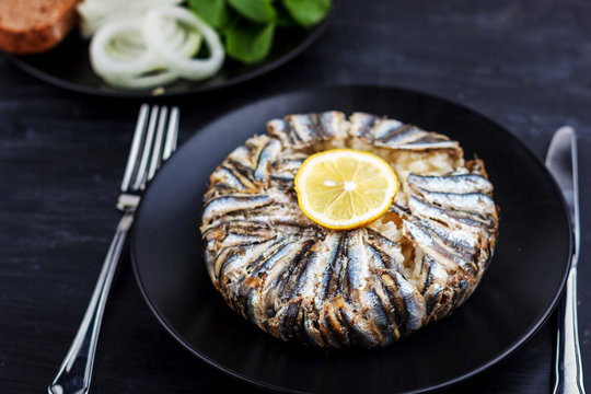 Pilaf with hamsi anchovy fish. Traditional Turkish food - Kapama Pilav - on black wooden table.