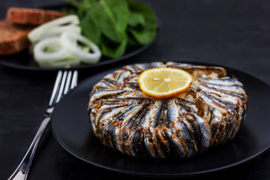Pilaf with hamsi anchovy fish. Traditional Turkish food - Kapama Pilav - on black wooden table.
