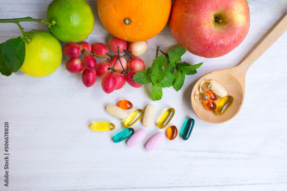 Wall mural multivitamin supplements from fruit on white wooden background