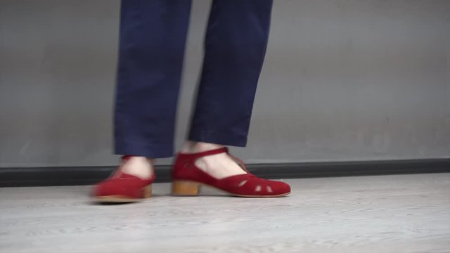 Girl dancing solo jazz swing dance. Dancer's legs close-up. Funny dance on grey background.
