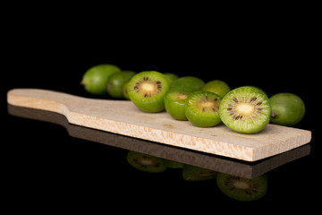 Group of lot of whole four halves of hardy green kiwi on wooden cutting board isolated on black...