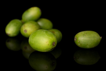 Group of seven whole hardy green kiwi isolated on black glass