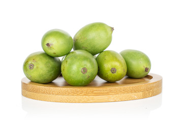 Group of six whole hardy green kiwi on round bamboo coaster isolated on white background