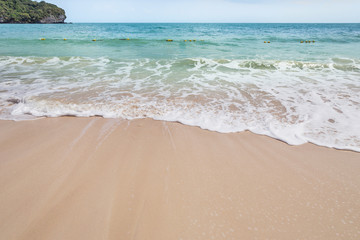 Fototapeta na wymiar Close up white soft wave rolling splash on empty tropical sandy beach in sunny day