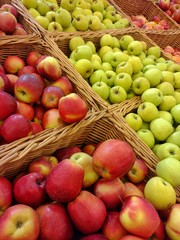 Many red and green apples in baskets at market