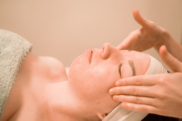 Beautiful young woman getting a face massage treatment at beauty salon