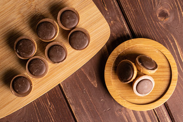 Lot of whole sweet brown toffee on bamboo cutting board on round bamboo coaster flatlay on brown...
