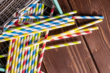 Lot of whole paper straw in shopping basket flatlay on brown wood