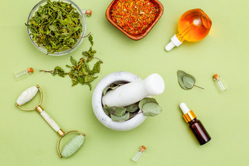 Dried herbs and face roller on green background. Organic skin care