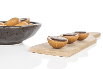 Lot of whole sweet brown toffee on wooden cutting board in glazed bowl isolated on white background