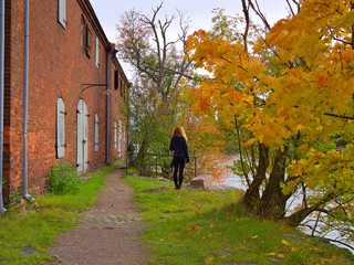 Woman under colourful fall coloured maple watching to the river