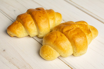Group of two whole sweet golden mini croissant on white wood