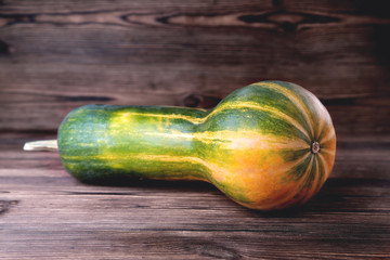Yellow-green oblong shaped pumpkin, natural wooden background, diet food, Halloween © Александр Юркевич