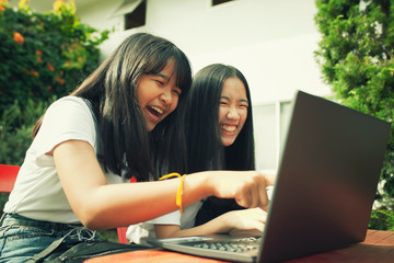 two asian teenager typing on computer labtop happiness emotion