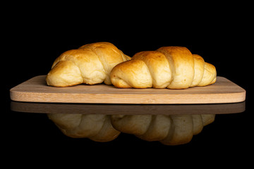 Group of two whole sweet golden mini croissant on bamboo cutting board isolated on black glass