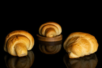 Group of three whole sweet golden mini croissant on bamboo coaster isolated on black glass