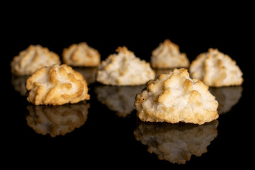 Group of seven whole homemade golden coconut biscuit isolated on black glass