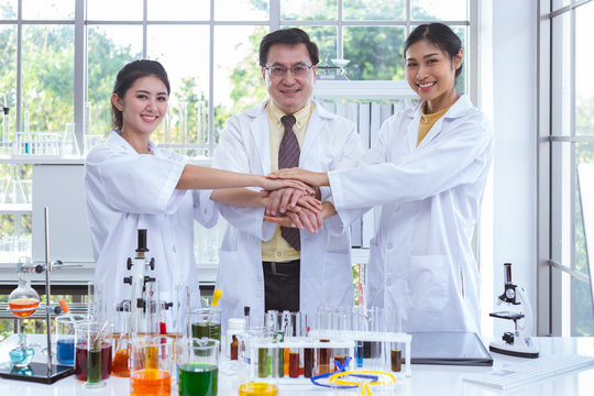 portrait of scientists showing team work joining hands together and contract with partners in laboratory, scient concept.