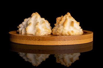 Group of two whole homemade golden coconut biscuit on bamboo coaster isolated on black glass