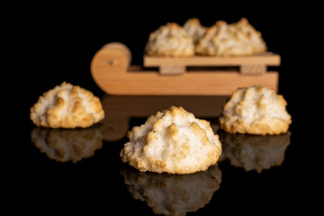 Group of seven whole homemade golden coconut biscuit with wooden sledge isolated on black glass
