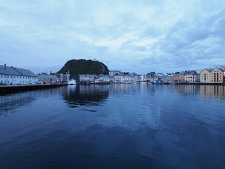Calm secessionist houses of european Alesund town reflected in water in Norway at blue hour