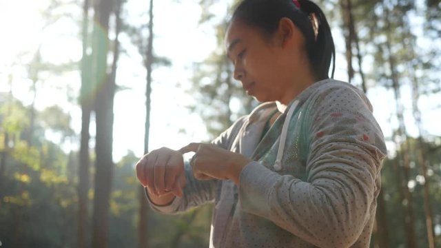 Asian woman touch on the screen of the smart watch on her wrist to setting fitness app before running in the garden. 
