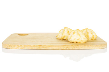 Group of three whole homemade golden coconut biscuit on bamboo cutting board isolated on white background