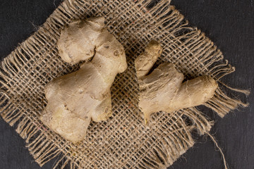 Group of two whole fresh brown ginger with jute fabric flatlay on grey stone