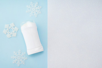 white antiperspirant with snow decor on blue background, copy space . winter body care products