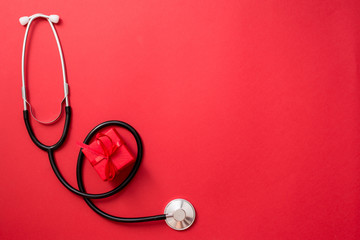 Medical stethoscope with gift box on red background. copy space, medicine greeting card