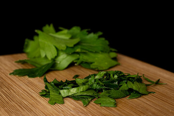 Lot of whole lot of pieces of fresh green parsley on bamboo cutting board isolated on black glass