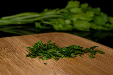 Lot of whole lot of pieces of fresh green parsley on bamboo cutting board isolated on black glass
