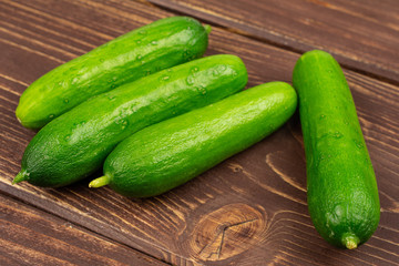 Group of four whole fresh green baby cucumber on brown wood