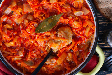 Pollock in tomato marinade with onions and carrots in a round shape, selective focus, top view