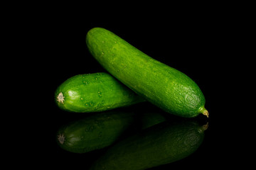 Group of two whole fresh green baby cucumber isolated on black glass