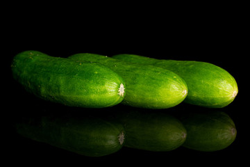 Group of three whole fresh green baby cucumber isolated on black glass