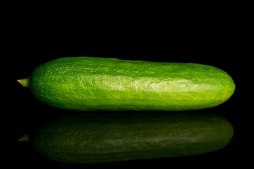 One whole fresh green baby cucumber isolated on black glass