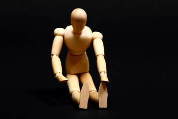 Conceptual image of a wooden manikin doing sit up's isolated on a black background