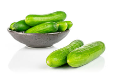 Lot of whole fresh green baby cucumber in dark ceramic bowl isolated on white background
