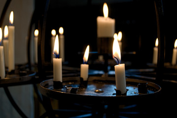burning white religious candles in the Church on a dark background, copy space