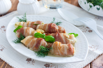 Oven bacon rolls with cheese baked on a white dish, horizontal