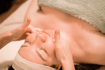 Obraz na płótnie Canvas Beautiful young woman getting a face massage treatment at beauty salon