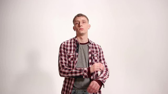 Man model in a plaid shirt posing on the white background wall. Indoors