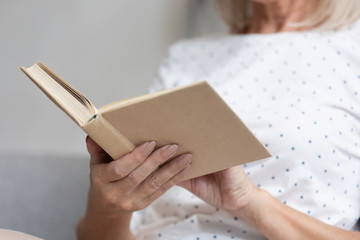Closeup focus on middle-aged female hands holding opened book