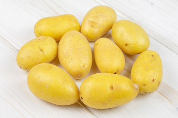 Lot of whole pale yellow potato on white wood