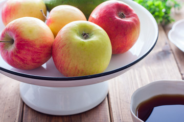 Fresh apples in an enameled stand on a wooden table and breakfast, selective focus