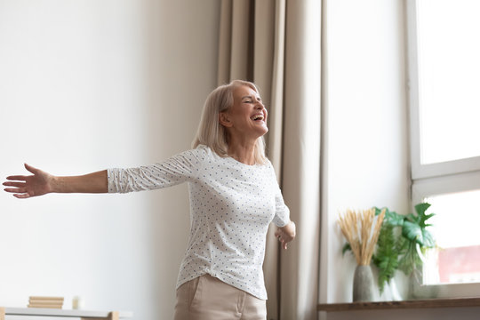 Carefree lively elderly woman stretched hands feels happy and healthy